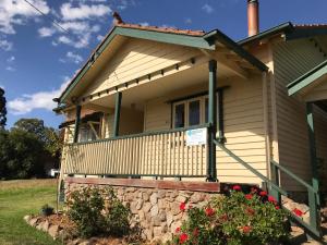 a house with a stone wall in front of it at Cherry Blossom Cottage - Beechworth-Getaways in Beechworth