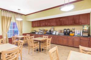 コーパスクリスティにあるHawthorn Extended Stay by Wyndham Corpus Christi Padre Isleのキッチン(木製のキャビネット、テーブル、椅子付)