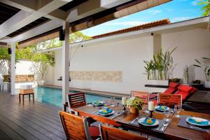 a dining room with a table and chairs and a pool at Temple Hill Residence Villa in Jimbaran