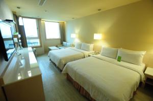 a hotel room with two beds and a couch at Kindness Hotel - Kaohsiung Guang Rong Pier in Kaohsiung