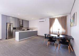 a kitchen and dining room with a table and a refrigerator at City Mews On Independence in Gaborone