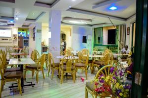 a restaurant with tables and chairs and people in the background at The Joy Hotel in Voi