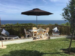 eine Terrasse mit einem Tisch, Stühlen und einem Sonnenschirm in der Unterkunft Casa Rosa Azul - Terracos de Benagil (Cliffside) in Benagil
