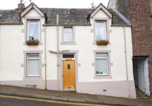 Casa blanca con puerta y ventanas marrones en Avonlea Self-Catering, en Crieff