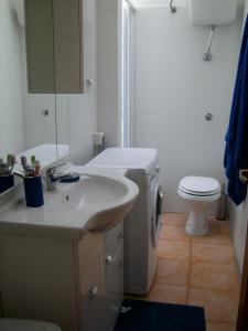 bagno bianco con lavandino e servizi igienici di Il Geranio a Badesi