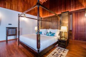 a bedroom with a canopy bed with a wooden wall at Symphony Summer Sands Beach Resort And Spa in Neil Island