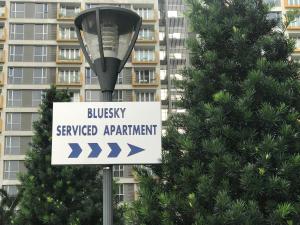 Bluesky Serviced Apartment Airport Plaza في مدينة هوشي منه: علامة على ضوء الشارع مع مبنى في الخلفية