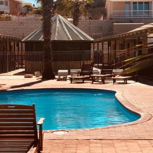 a swimming pool with two benches next to a building at Bay Lodge in Denham +39 photos
