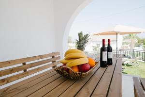 una cesta de fruta y dos botellas de vino en una mesa en Villa Irini & Villa Vasiliki en Afantou