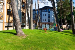 drzewo w trawie przed budynkiem w obiekcie Mi Casa Holidays Rezydencja Park Rodzinna w mieście Mielno