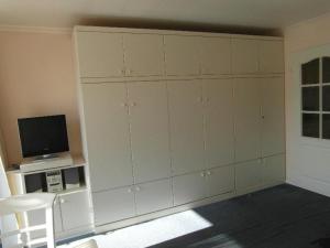 Cette chambre dispose d'une grande armoire blanche et d'une télévision. dans l'établissement Haus-Metropol-Neues-Kurzentrum-Appartement-38, à Westerland