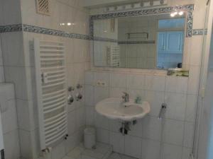La salle de bains blanche est pourvue d'un lavabo et d'un miroir. dans l'établissement Haus-Metropol-Neues-Kurzentrum-Appartement-38, à Westerland