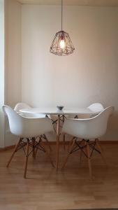 a dining room table with white chairs and a light fixture at Basel Charme Apartments in Basel