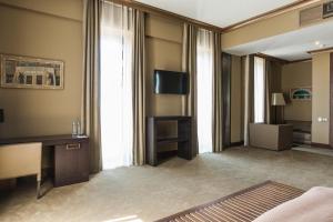 a hotel room with a desk and a television at Soho Grand Hotel in Azov