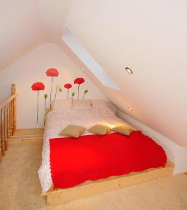 ŻarnowskaにあるApartament Makowe Polaのベッドルーム1室(屋根裏部屋に赤いベッド1台付)