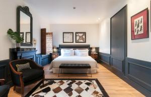 a bedroom with a bed and a chair and a mirror at La Casa del Presidente Small Luxury Hotels in Ávila