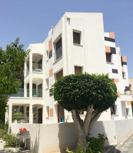 un edificio blanco con un árbol delante en Modern Seaview Beach Studio Limassol en Limassol