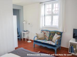 a bedroom with a blue chair and a window at Haus zur Eselsbrücke in Tangermünde