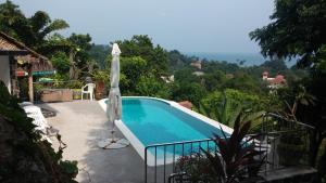 a swimming pool with an umbrella next to a house at Samui Grand Rock in Lamai