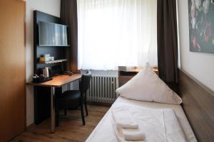 ein Hotelzimmer mit einem Bett, einem Schreibtisch und einem Fenster in der Unterkunft Center Hotel Essen in Essen