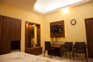 een slaapkamer met een bed, een bureau en stoelen bij Om Sai Villa Guesthouse in Calcutta