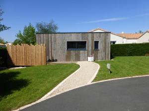 a house with a fence and a driveway at La cabane du Bonheur in Les Herbiers