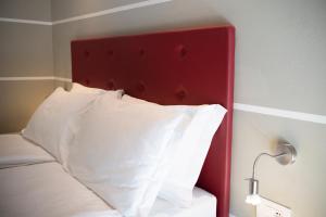 1 cama con cabecero rojo y almohadas blancas en Hotel Imperial ***S, en Garda