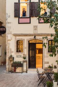 Una donna che guarda fuori dalla finestra di un edificio di Harismari Cozy Hotel a Chania