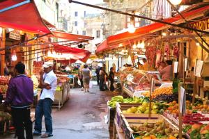 a group of people walking around a market with fruits and vegetables at Il Tempo Ritrovato - Locazione ad uso turistico in Palermo