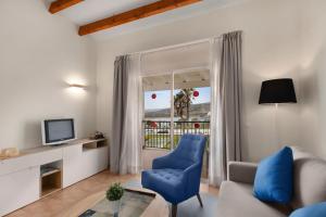 a living room with a blue chair and a television at TRH Tirant Playa in Fornells