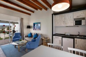 a kitchen and living room with blue chairs and a table at TRH Tirant Playa in Fornells