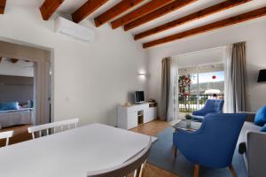 a living room with a white table and blue chairs at TRH Tirant Playa in Fornells