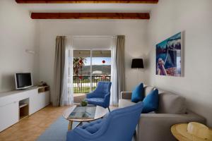 a living room with blue chairs and a couch at TRH Tirant Playa in Fornells