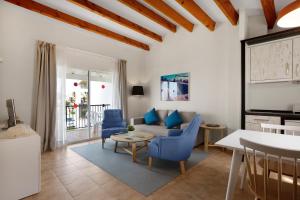 a living room with blue chairs and a couch at TRH Tirant Playa in Fornells