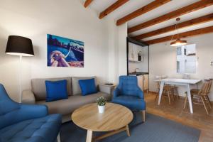 a living room with a couch and blue chairs and a table at TRH Tirant Playa in Fornells