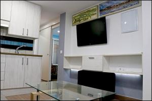 kuchnia ze szklanym stołem i telewizorem na ścianie w obiekcie Apartamento Baluarte w mieście Conil de la Frontera