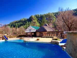 a large swimming pool in front of a house at 124 Fairways Drakensberg Gardens in Underberg
