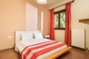 a bedroom with a bed with red curtains and a window at Filio House in Stalos