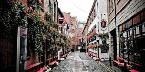 a narrow street with flowers on the sides of buildings at Rooftop Apartments in Belfast +7 photos