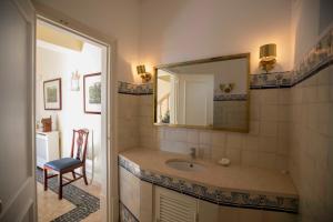 un bagno con un lavandino, uno specchio e una sedia di Quinta da Paciencia a Sintra Altre 17 foto