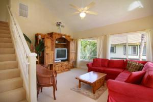 a living room with a red couch and a tv at Regency at Poipu Kai #924 in Koloa