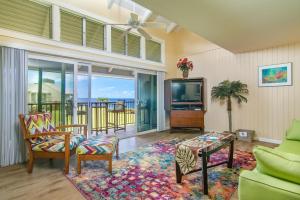 a living room with a tv and a couch and chairs at Pali Ke Kua #241 in Princeville