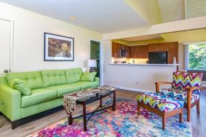 a living room with a green couch and two chairs at Pali Ke Kua #241 in Princeville