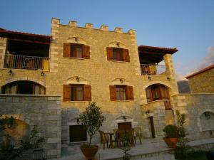 - un grand bâtiment en pierre avec une table devant dans l'établissement Atha-Tina:Traditional Stone Homes, à Agios Nikolaos