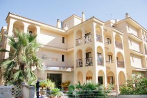 un grand bâtiment avec un palmier en face dans l'établissement Hotel Morlans, à Paguera
