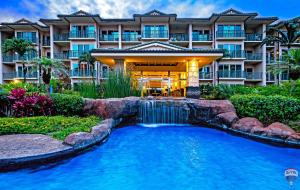 un hôtel avec une cascade en face d'une piscine dans l'établissement Waipouli Beach Resort G-404, à Kapaa