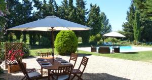 une table avec un parasol à côté d'une piscine dans l'établissement Mas des Bougainvillees, à Sernhac