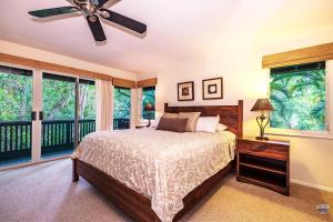 um quarto com uma cama e uma ventoinha de tecto em Kauai Tree House em Wainiha