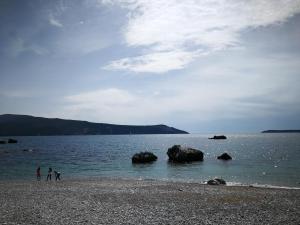 dos personas de pie en una playa cerca del agua en Apartments La Dolce Vita en Herceg-Novi