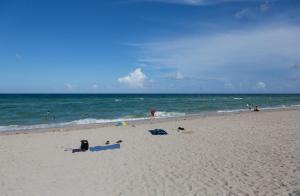 un grupo de personas en una playa cerca del océano en Thunderbird Beach Hotel, en Sunny Isles Beach